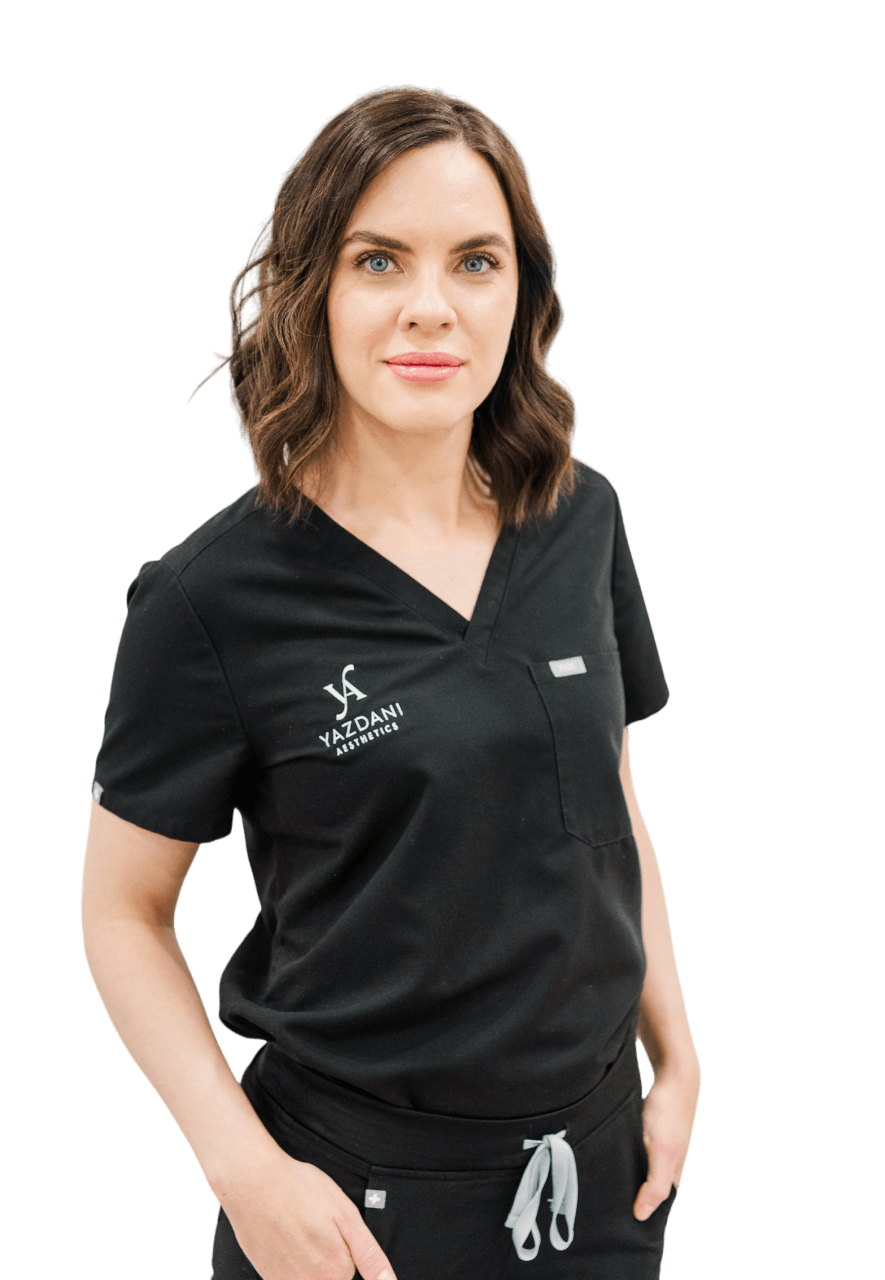 Woman wearing a black medical scrub top with the Yazdani Aesthetics logo, standing with a neutral expression.